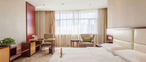 Habitación de hotel con una cama grande, un escritorio, una silla, una mesita y un televisor.