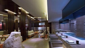 A modern restaurant with a long counter, seating area, and a stone wall. - Sheraton Fuzhou Hotel (Fuzhou)