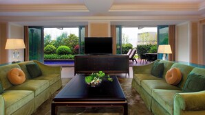 A living room with two green sofas, a black coffee table, and a flat-screen TV. - Sheraton Fuzhou Hotel (Fuzhou)