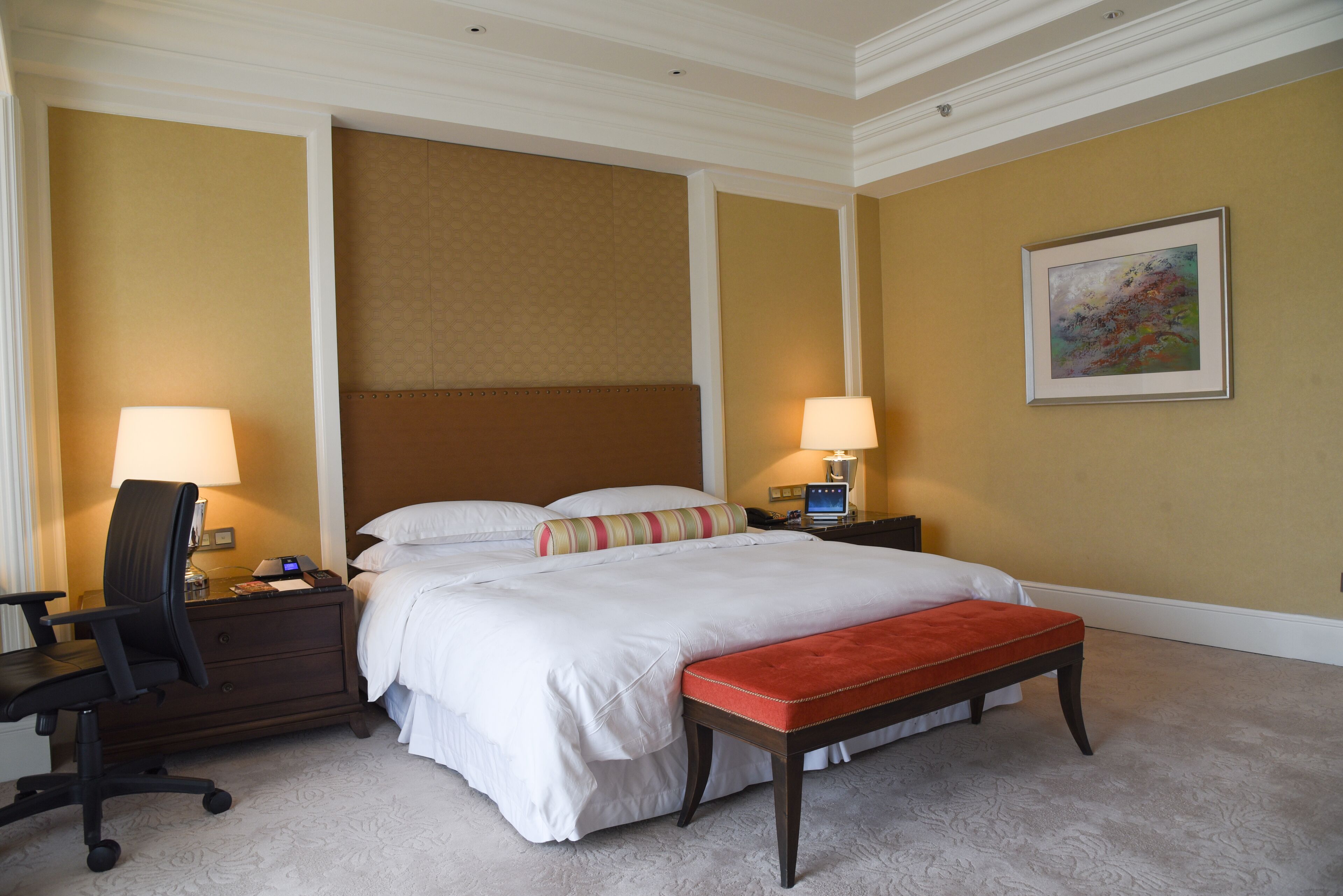 A hotel room with a large bed, two bedside tables with lamps, a desk, and a chair.
