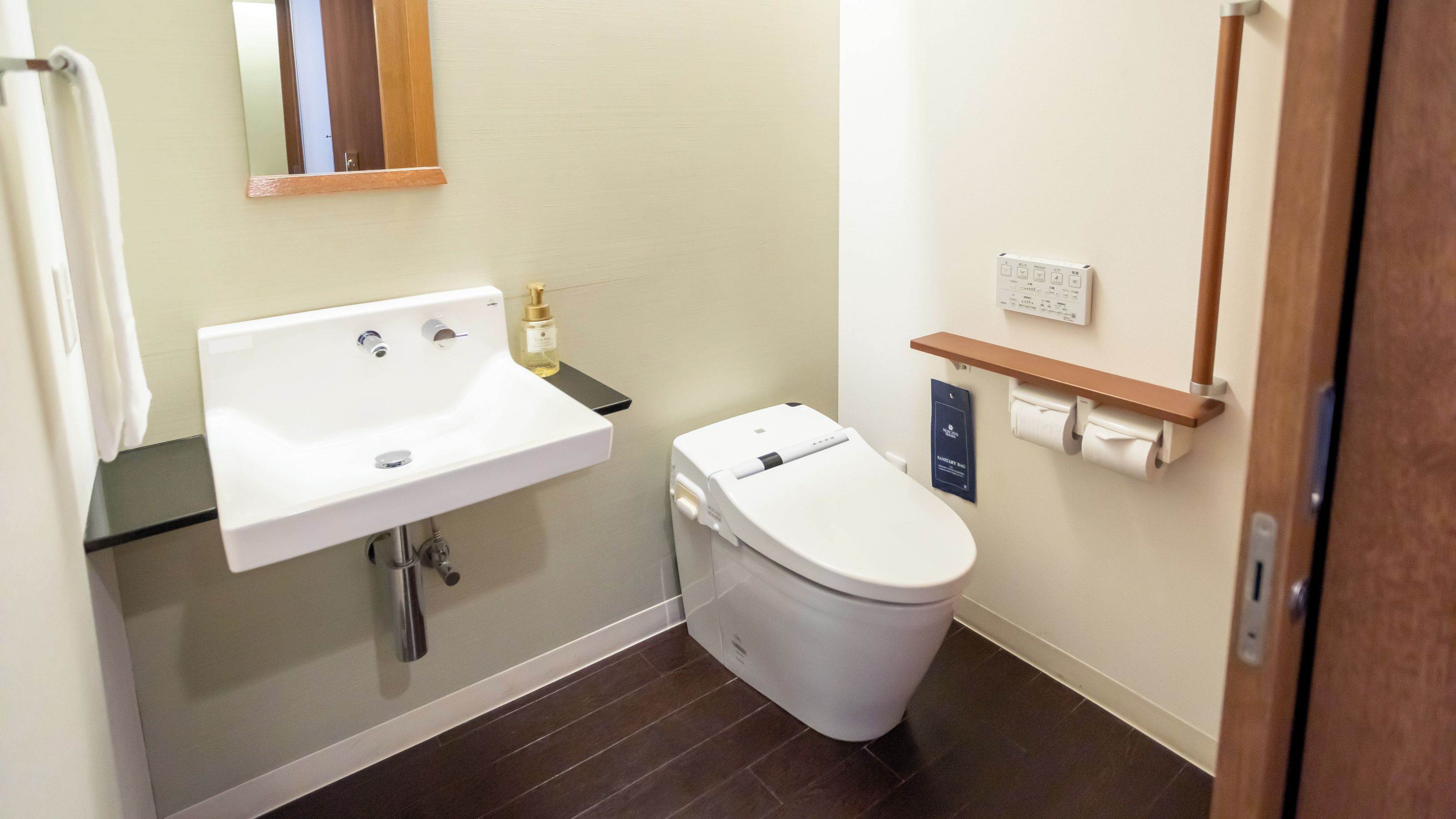 A bathroom with a white sink, a toilet, a mirror, and a towel rack.