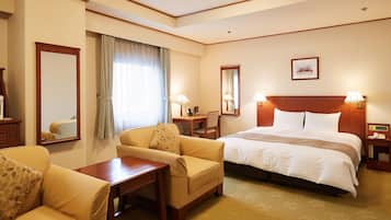 A hotel room with a bed, a sofa, a desk, and a chair.