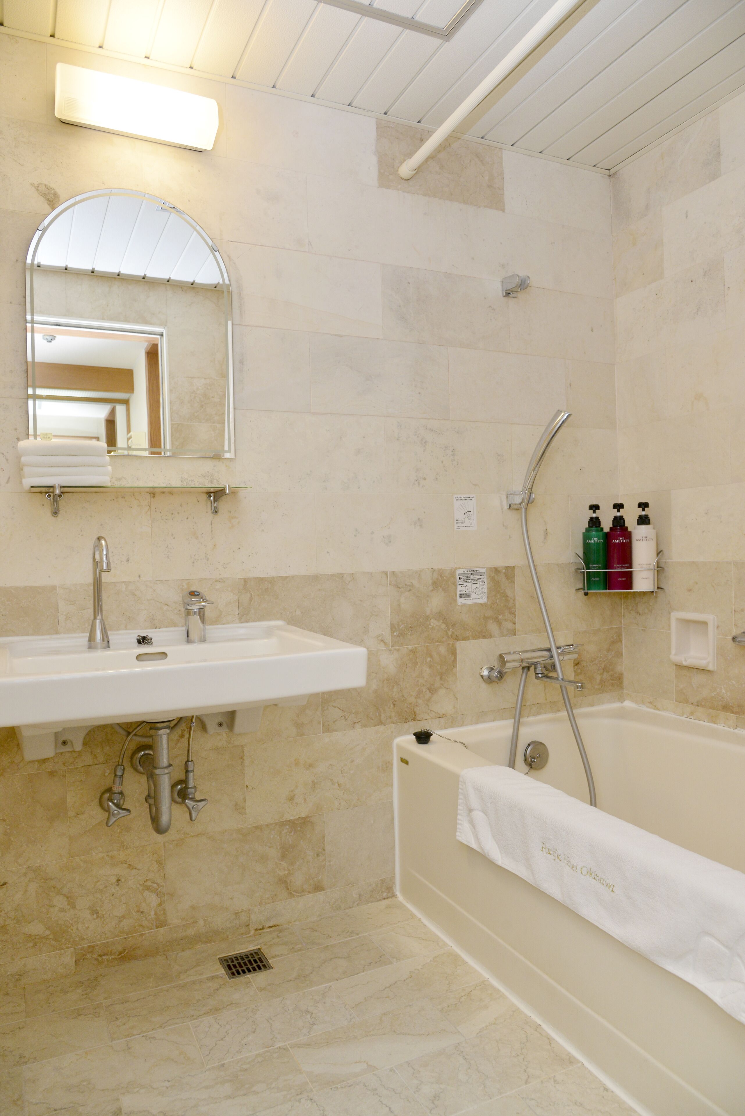 A bathroom with a sink, mirror, shower, and towel rack.