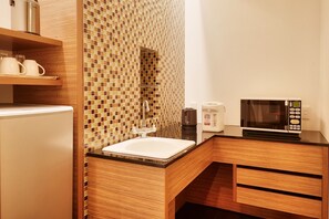 A modern bathroom with a wooden vanity, a sink, a mirror, a coffee maker, and a microwave. - Pacific Hotel Okinawa (Naha)
