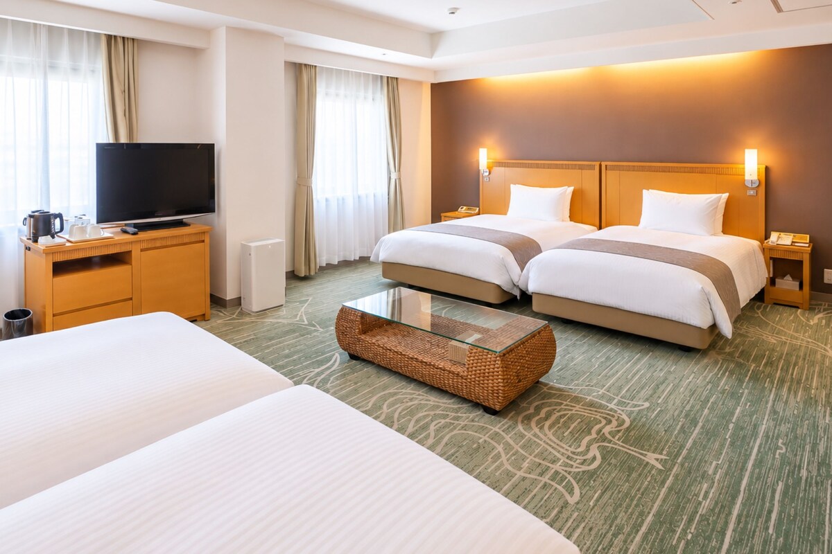 A hotel room with two beds, a television, a coffee machine, and a waste bin.