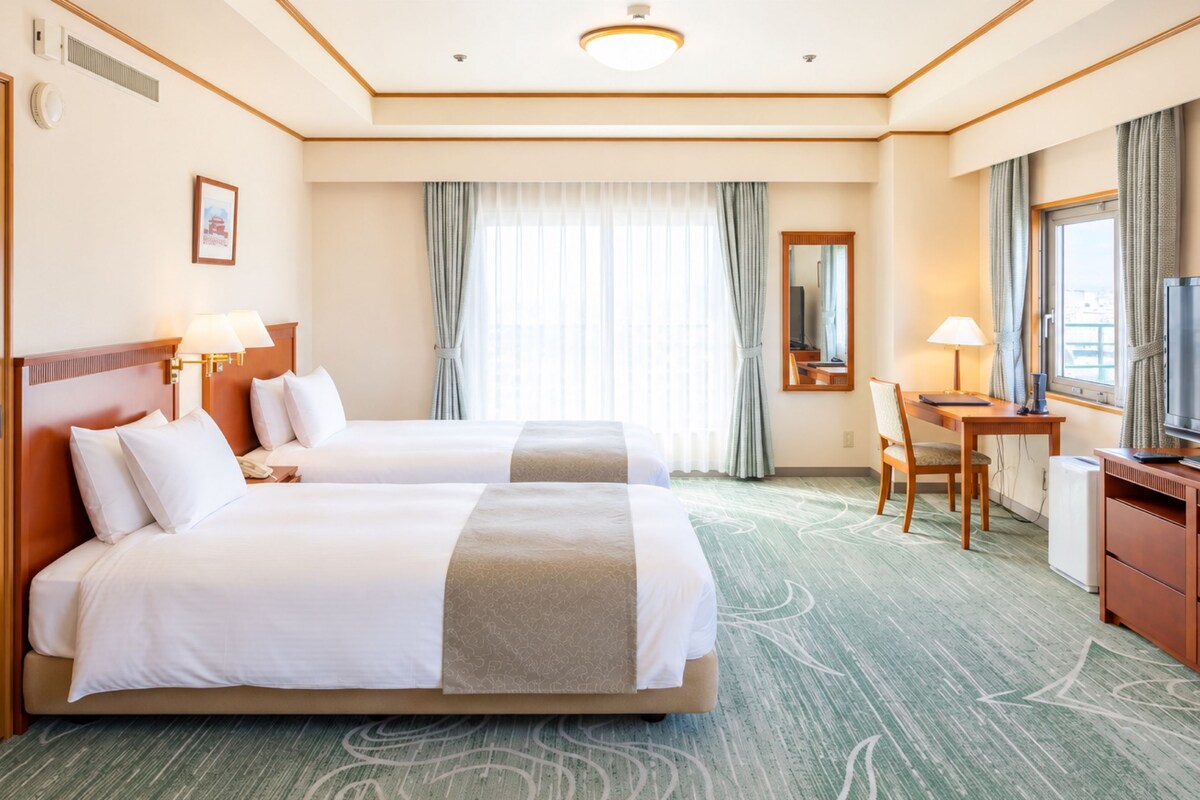 A hotel room with two beds, a desk, a television, and a mirror.