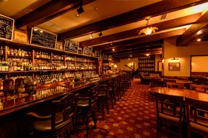 A bar area with wooden furniture, a long counter with bottles, and a patterned carpet. - Pacific Hotel Okinawa (Naha)
