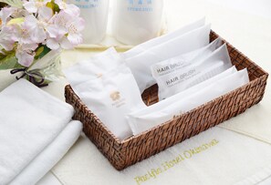 A wicker basket with hairbrushes and a towel, alongside a bottle labeled "STERILIZED" and a bouquet of flowers. - Pacific Hotel Okinawa (Naha)