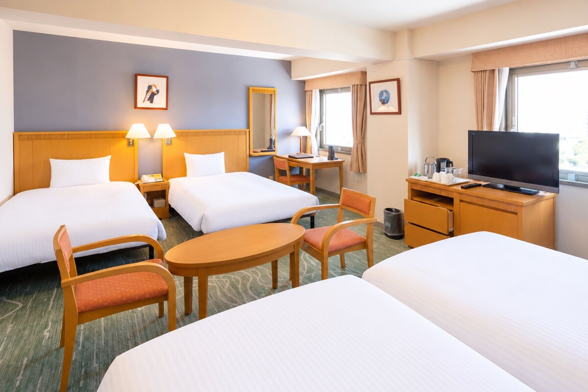A hotel room with two beds, a desk, a chair, a television, and a window with curtains.