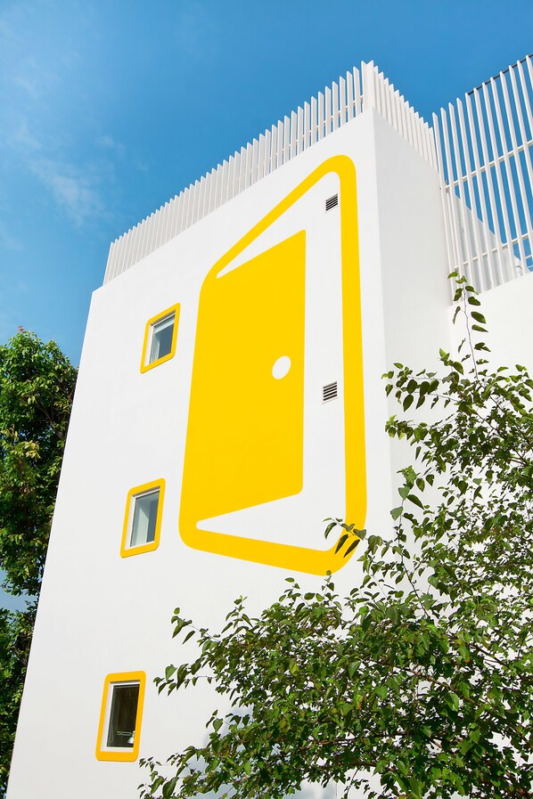 A building with a distinctive yellow door and white exterior. - Bloomrooms @ Link Road (New Delhi)