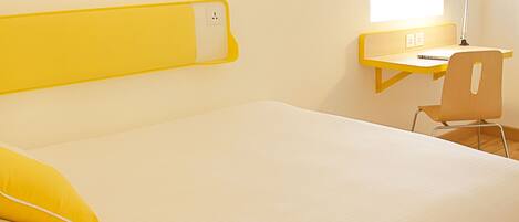 A room with a bed, a desk, a chair, and a lamp.