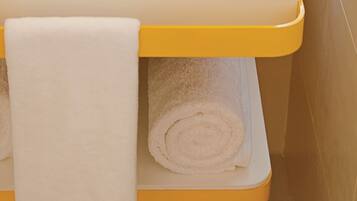 Un baño con un perchero amarillo que sostiene dos toallas blancas.
