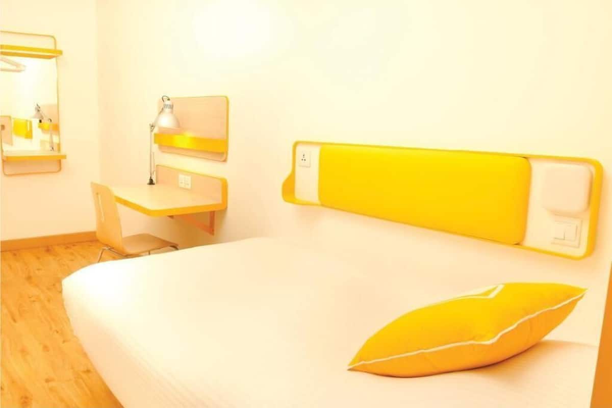 A room with a bed, a desk, a chair, a lamp, and a mirror.