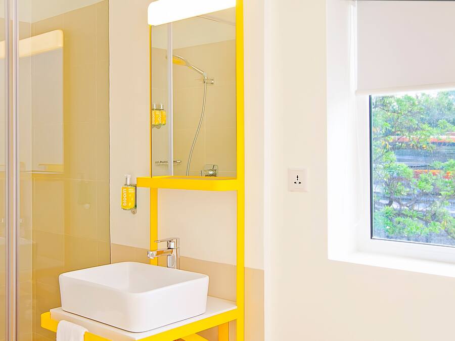 A bathroom with a glass-enclosed shower, a white sink, and a yellow vanity.