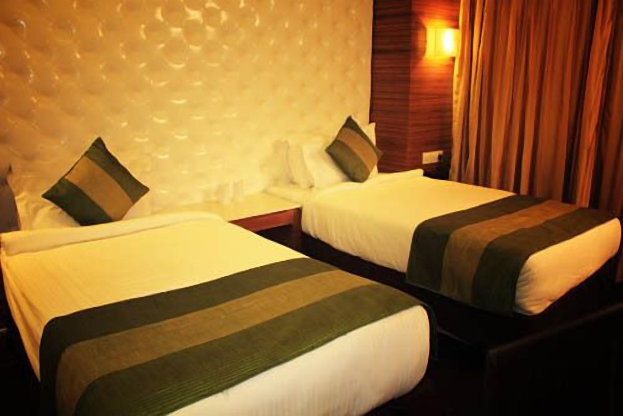 Habitación de hotel con dos camas, cada una con colcha y almohadas a rayas.