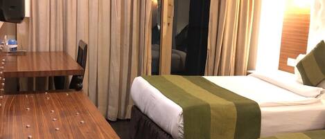 A hotel room with two beds, a wooden table, and a TV.