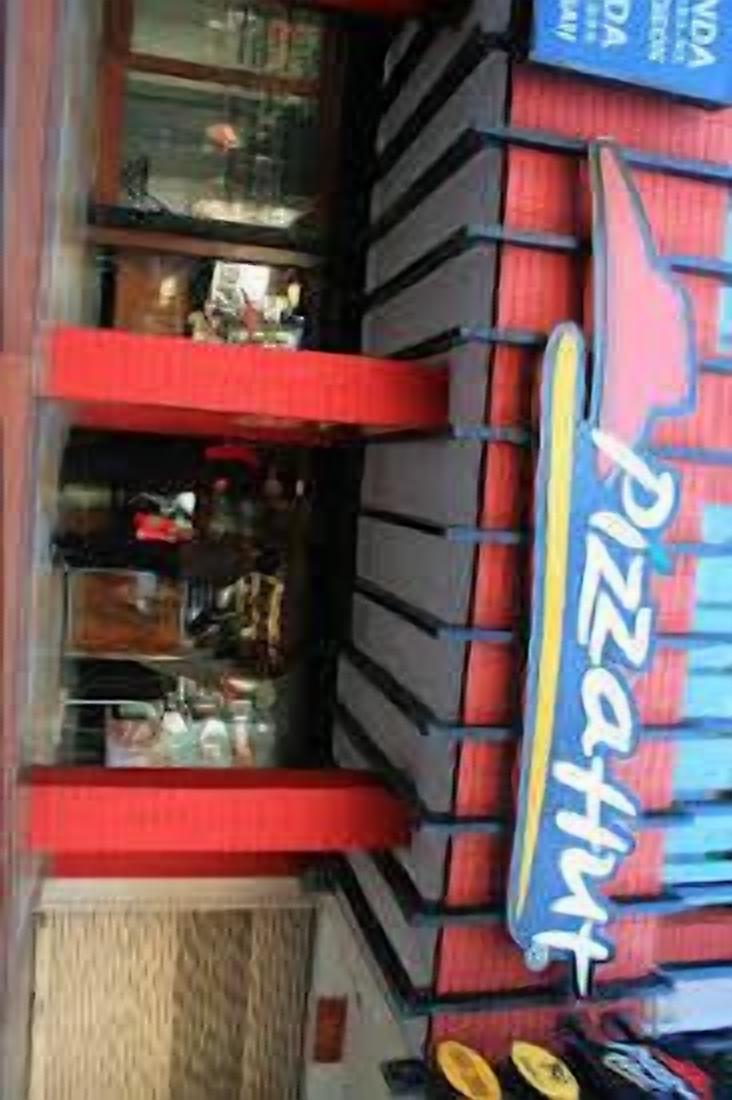 Un restaurant de pizzas avec une enseigne rouge et bleue, une vitrine et une porte.