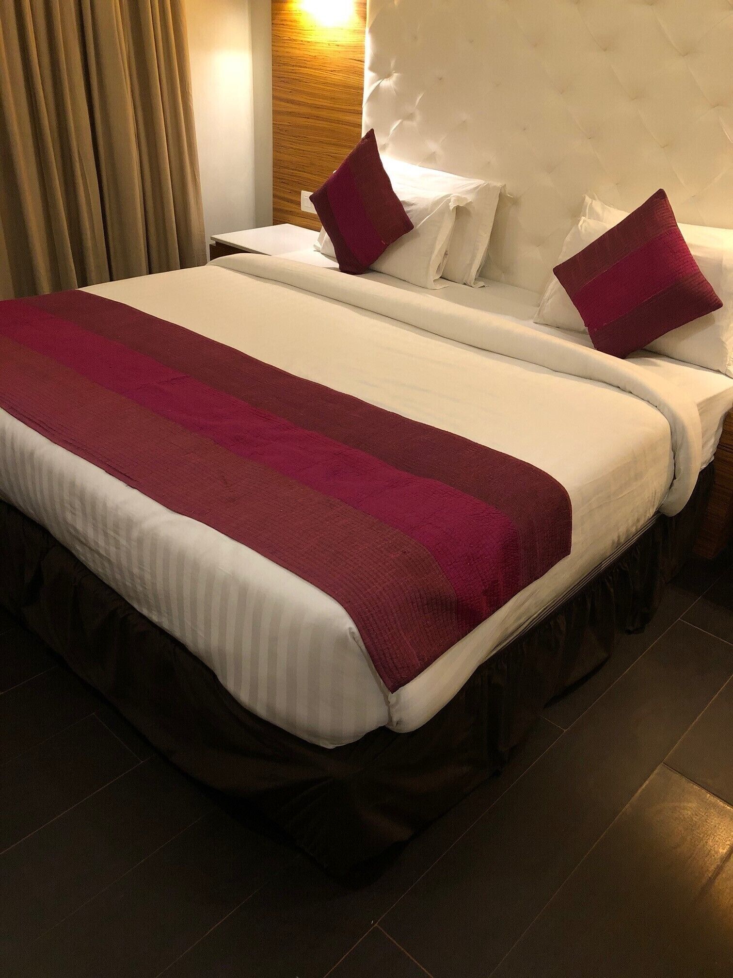 Camera d'albergo con due letti, una grande coperta a righe rosse e bianche e una testiera in legno.