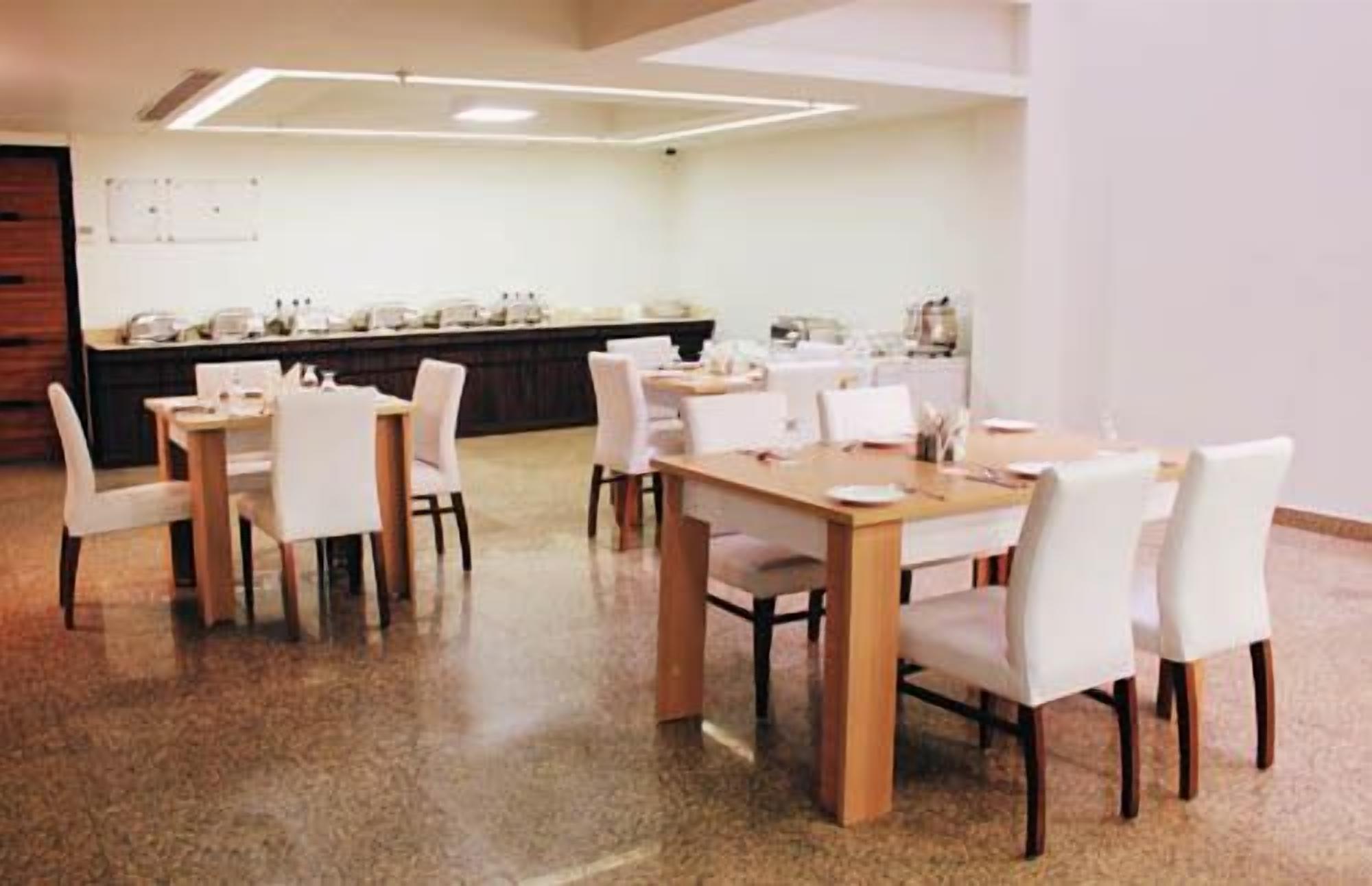 A conference room with multiple tables and chairs, a long counter with various items, and a whiteboard on the wall.