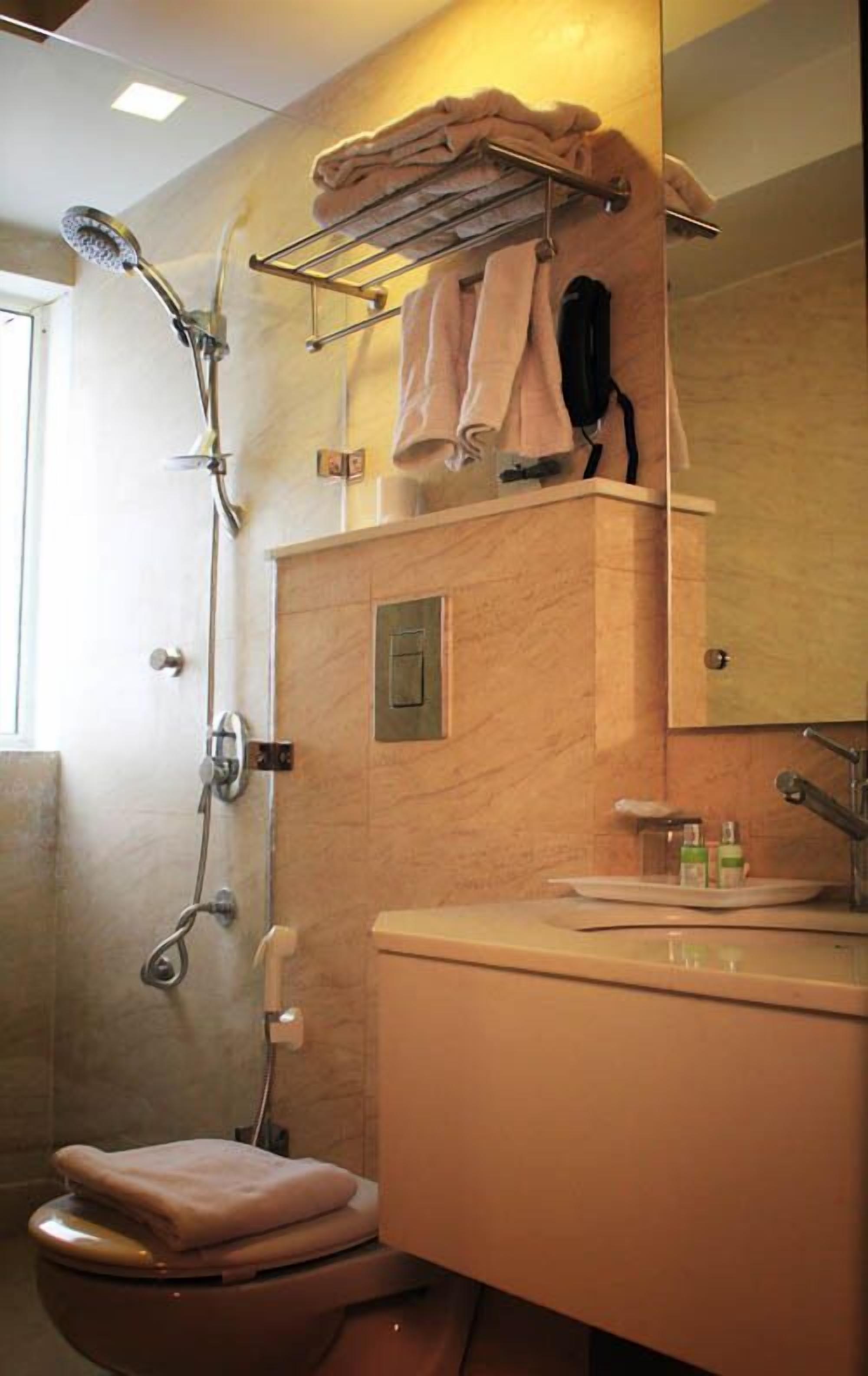 A bathroom with a shower, toilet, sink, and towel rack.