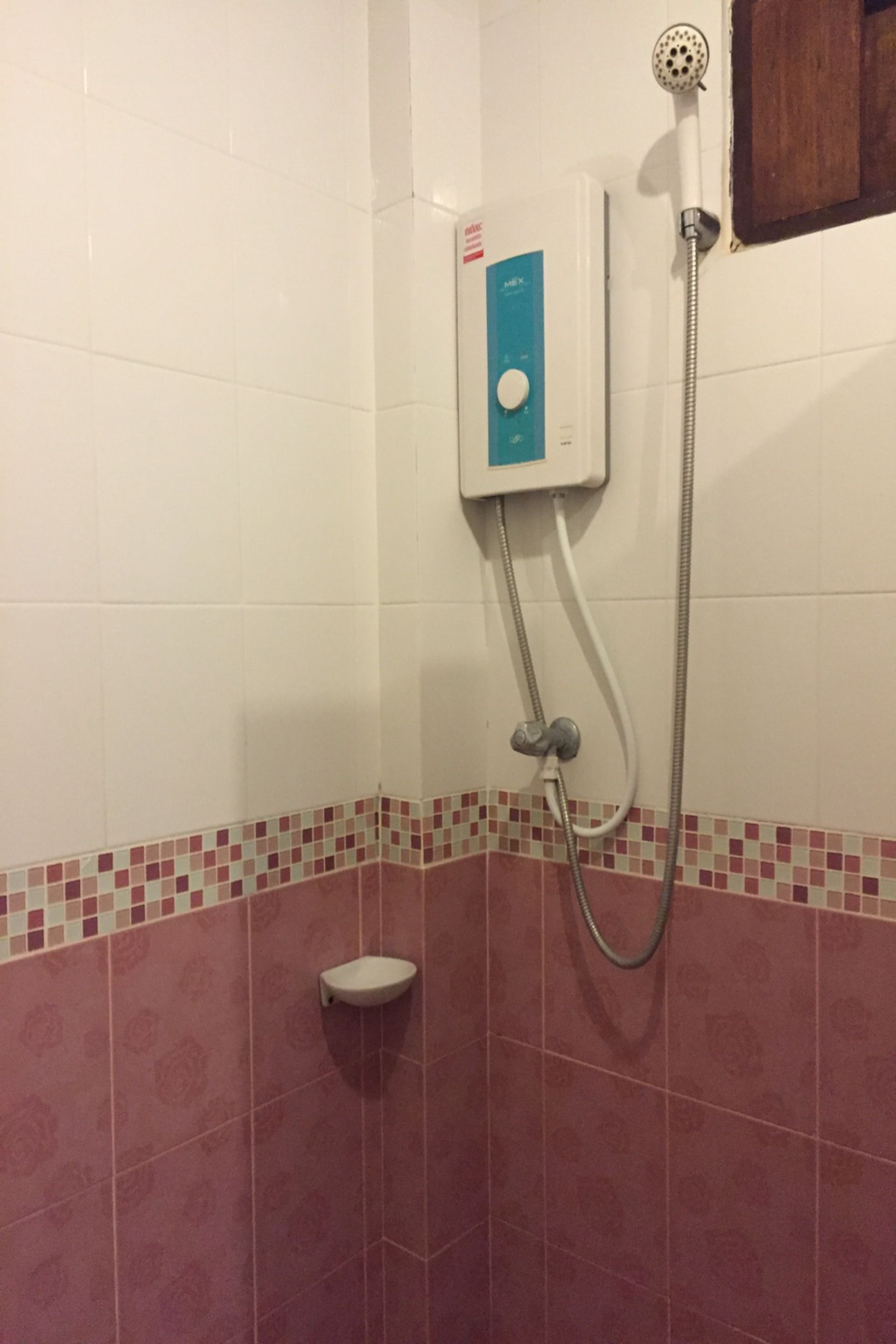 Un bagno con doccia, pannello comandi a parete e piccolo lavandino.