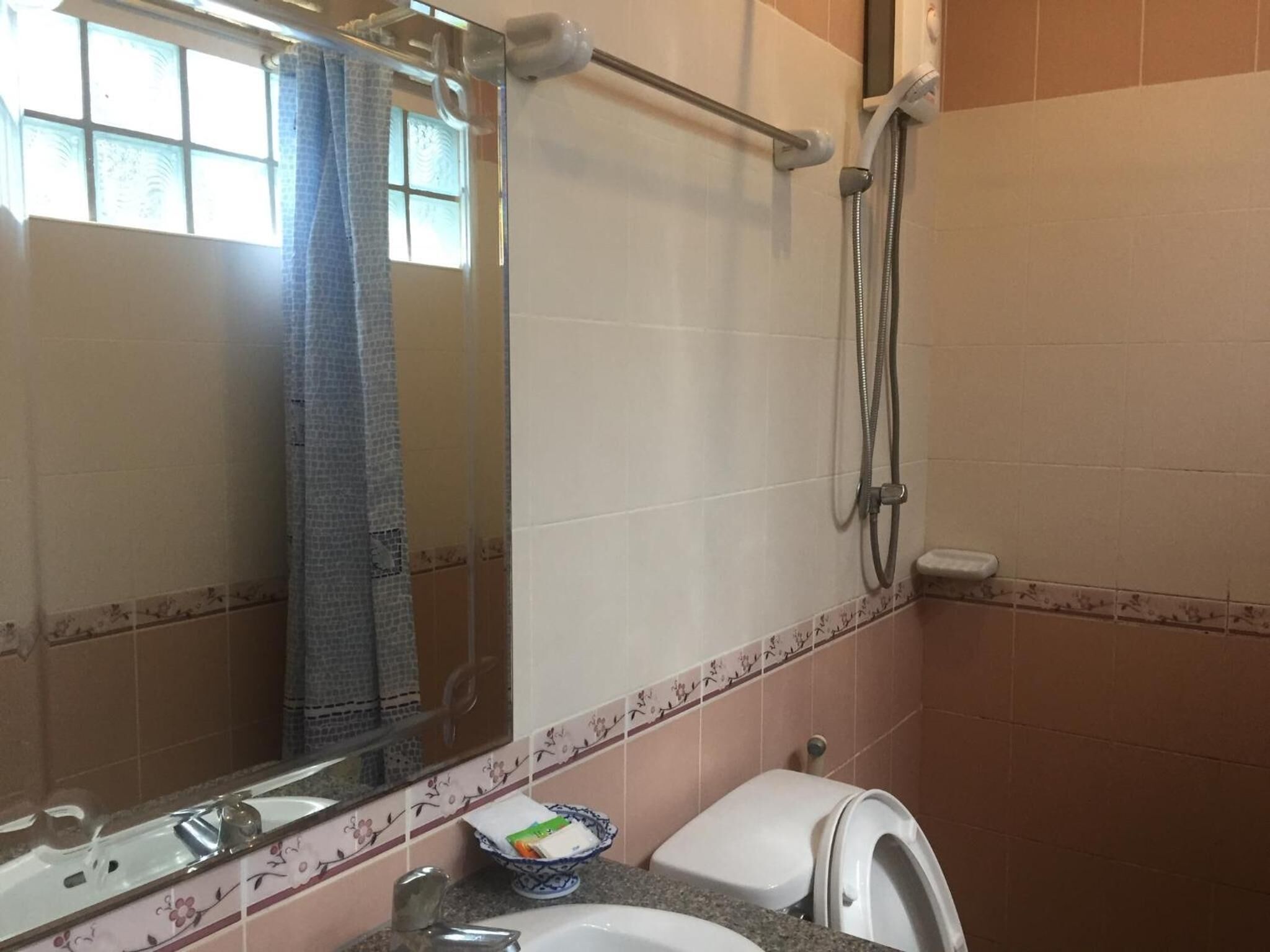 A bathroom with a shower, toilet, sink, and a large mirror.