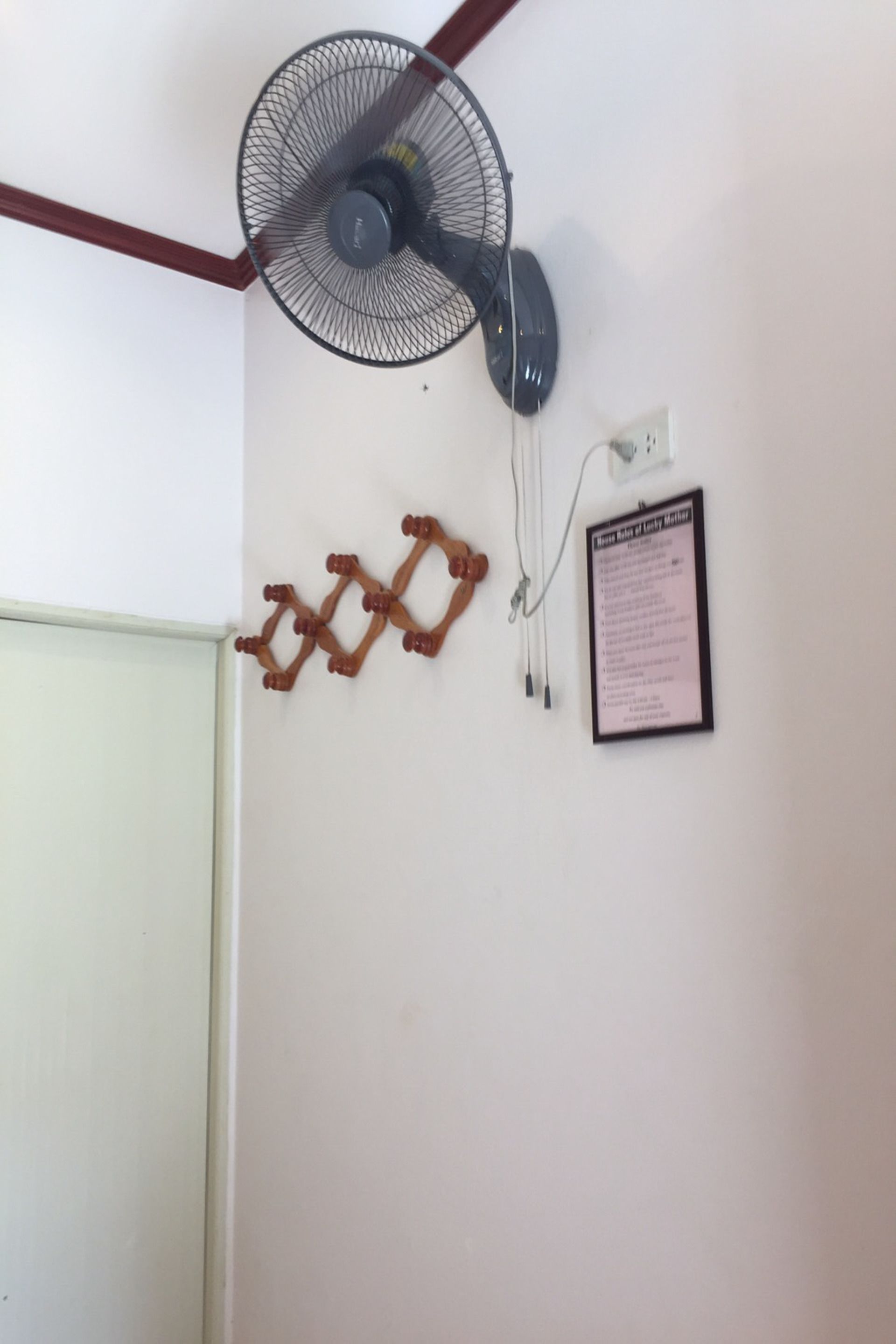 A ceiling fan, a wall-mounted light switch, and a framed sign on a white wall.
