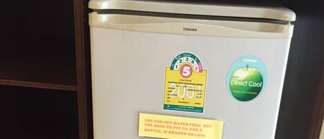 Un refrigerador con el logotipo de Toshiba, una etiqueta de Direct Cool y un letrero amarillo sobre tarifas de agua.