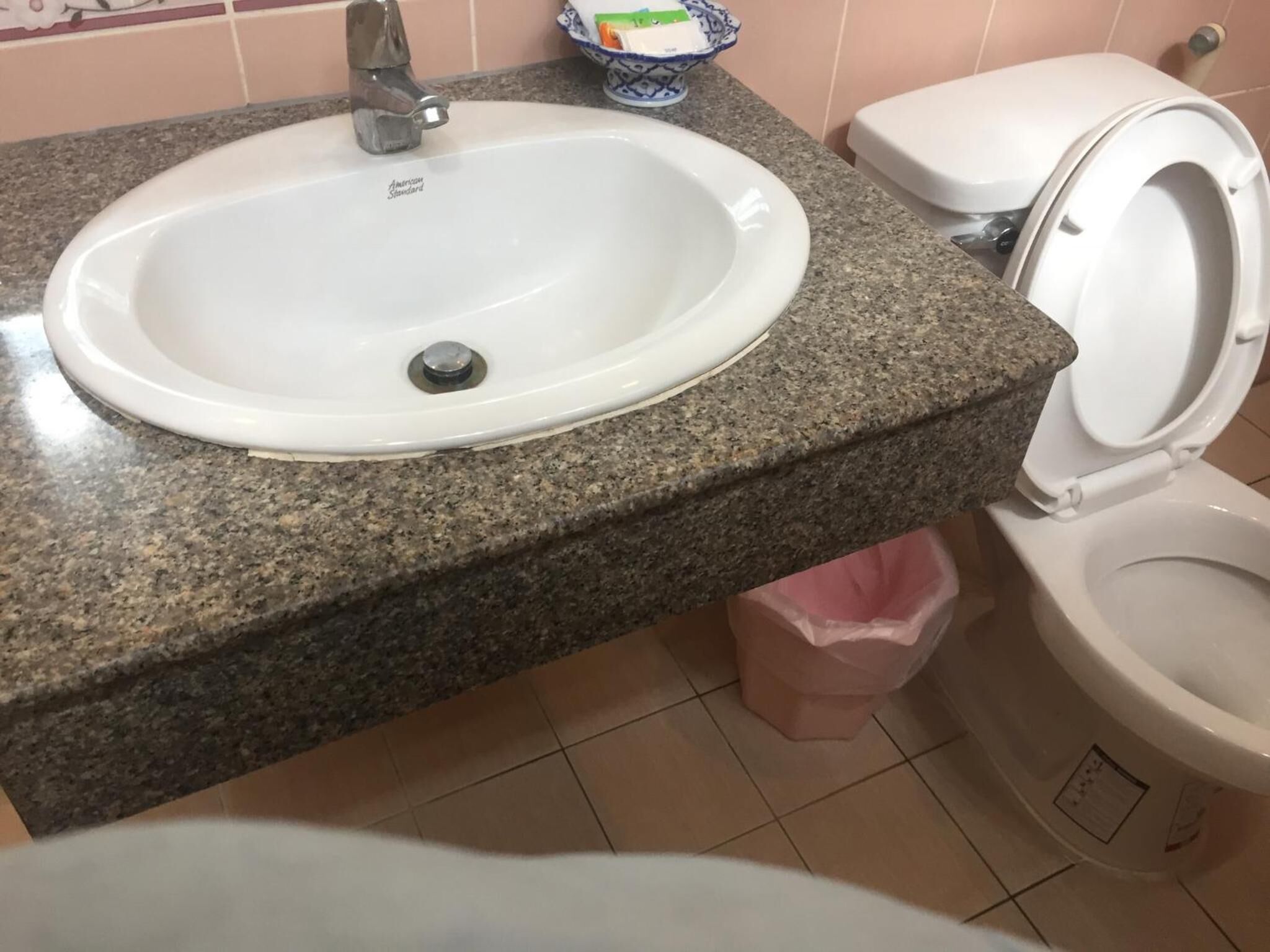 A bathroom with a white sink, granite countertop, and a toilet.