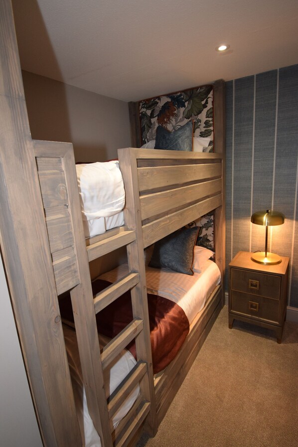 A bunk bed with a ladder, a bedside table with a lamp, and a floral wall hanging. - The Elphinstone Hotel (Biggar)