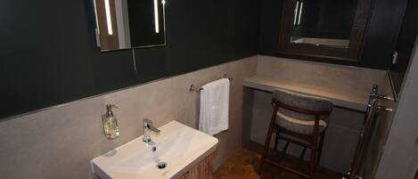 Un baño moderno con un lavabo blanco, tocador de madera y un espejo sobre el lavabo.