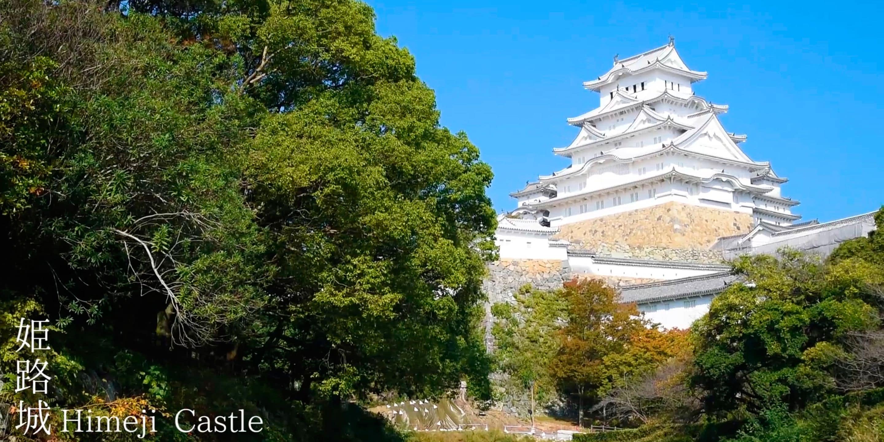 Himeji Castle with its traditional Japanese architecture, surrounded by lush greenery.