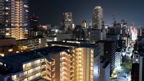 A cityscape at night with illuminated buildings, including a prominent high-rise with a unique rooftop structure. - Kobe Sannomiya Union Hotel (Kobe)