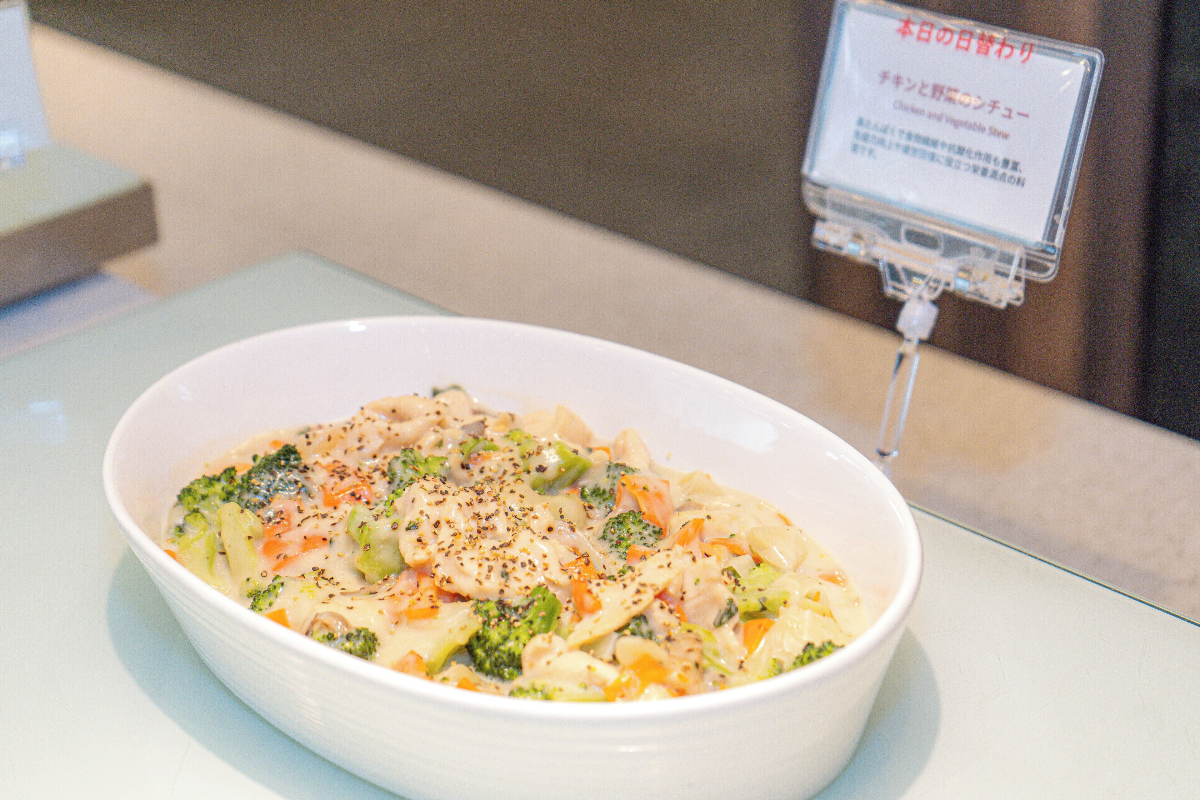 A bowl of soup with vegetables and chicken, served in a white bowl on a table.