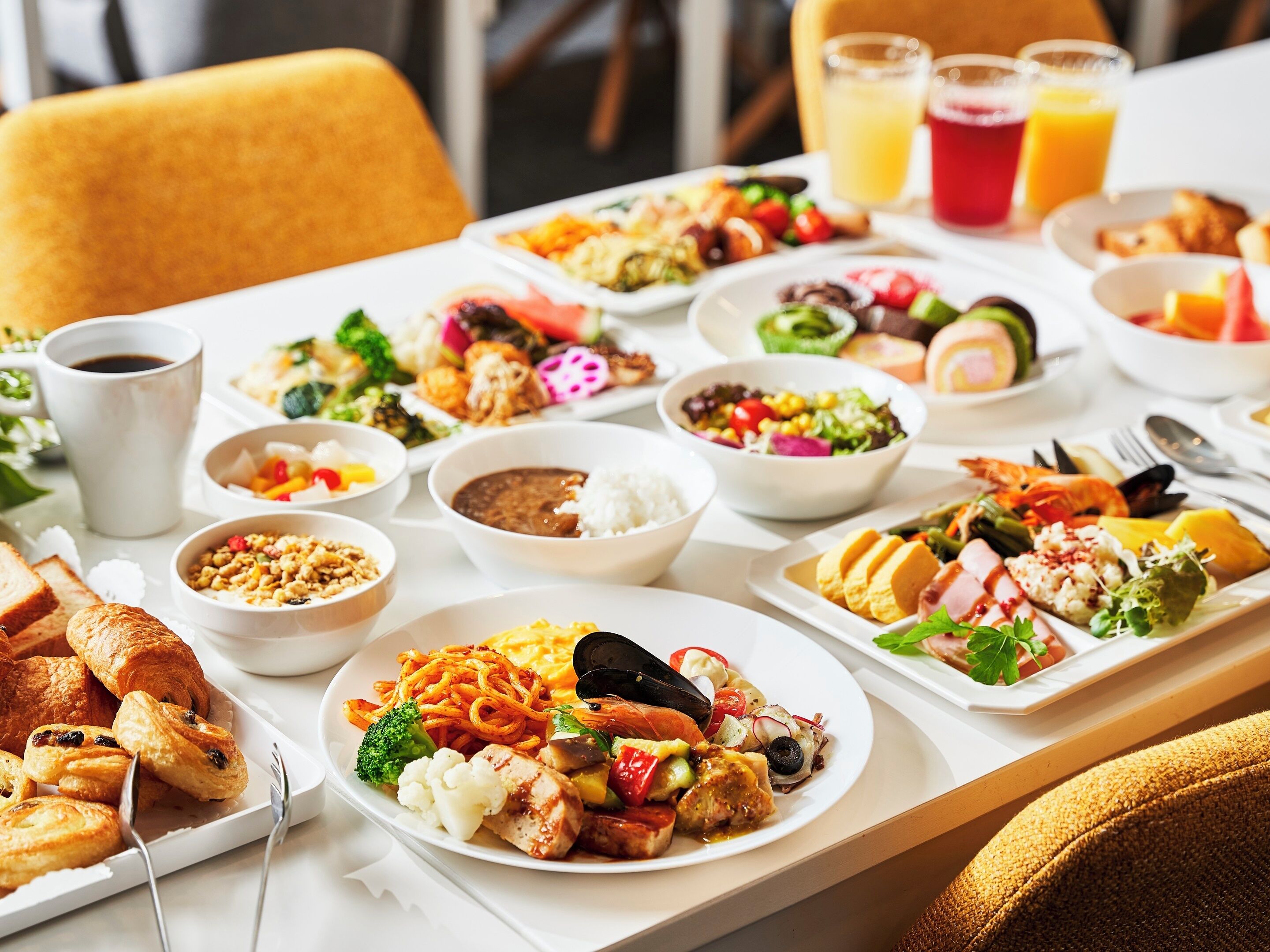 Una mesa servida con diversos platos, como pasta, ensaladas y pan, que sugiere un ambiente para comer.