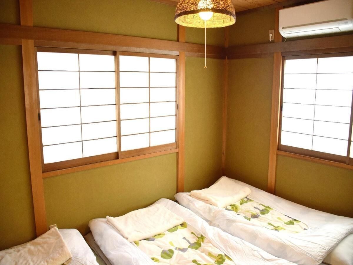 Een kamer met twee bedden, houten balken en een shoji-scherm raam.
