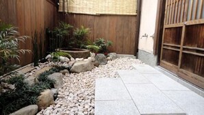 A traditional Japanese garden with a wooden fence, a stone pathway, and various plants. - Guest House Higashiyama (Kyoto)