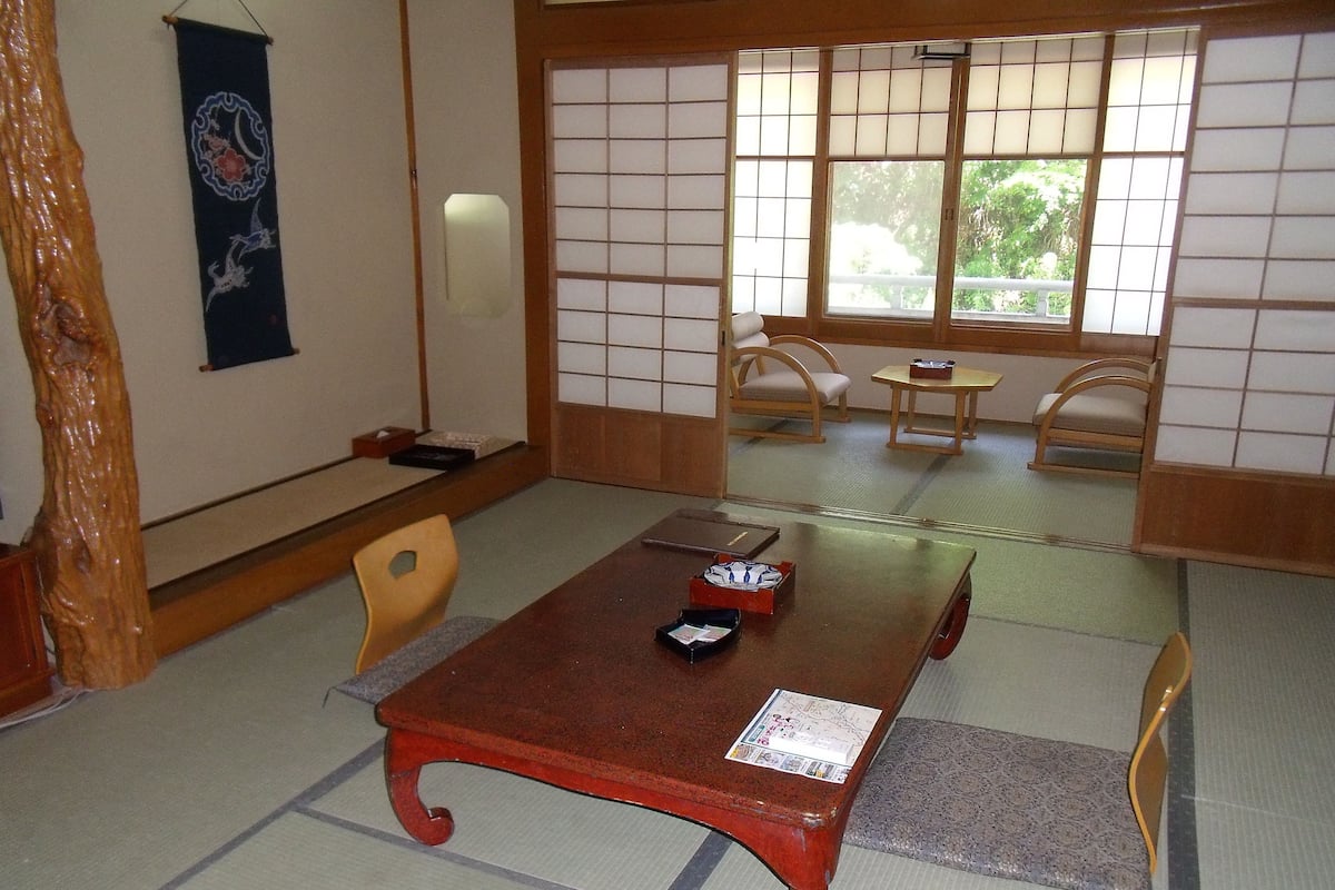 Una habitación tradicional japonesa con suelo de tatami, una mesa de madera baja y paneles shoji.