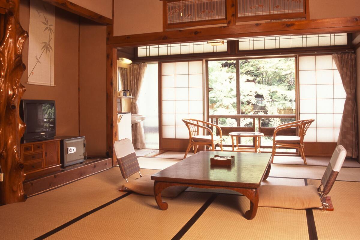Una habitación japonesa tradicional con suelo de tatami, una mesa baja y sillas de madera.