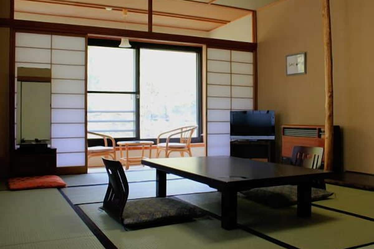 Una habitación tradicional japonesa con suelo de tatami, una mesa baja, un televisor y una radio.