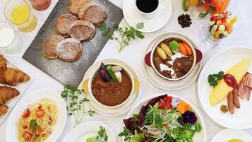 A variety of dishes including pasta, soup, and a salad, arranged on a table with drinks and bread.