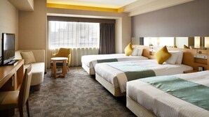 A hotel room with two beds, a desk, a chair, a TV, and a large window with curtains.