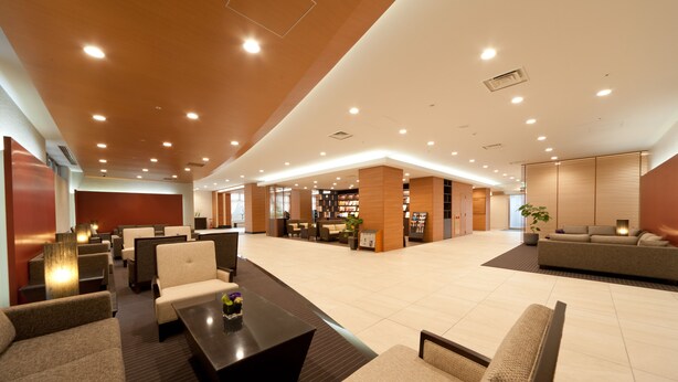 A spacious lobby with multiple seating areas, a reception desk, and a bookshelf.