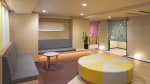 A modern waiting area with a sofa, a small round table, and a colorful ottoman.