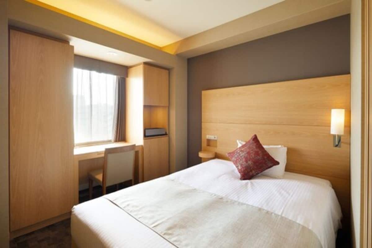 A hotel room with a bed, a desk, and a chair.