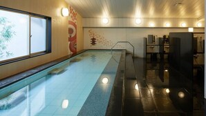 A swimming pool with a tiled floor, a wooden wall with a decorative panel, and a ceiling with recessed lighting.