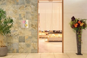 A reception area with a stone wall, a potted plant, a decorative sign, and a floral arrangement.