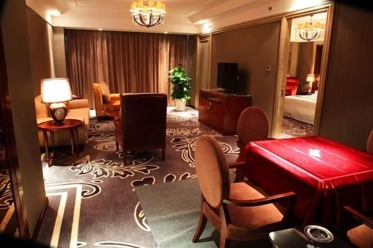 Una habitación de hotel con una mesa de comedor, sillas, televisor, cama y una planta.