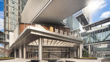Un edificio moderno con una entrada destacada, grandes ventanales y una fuente central.