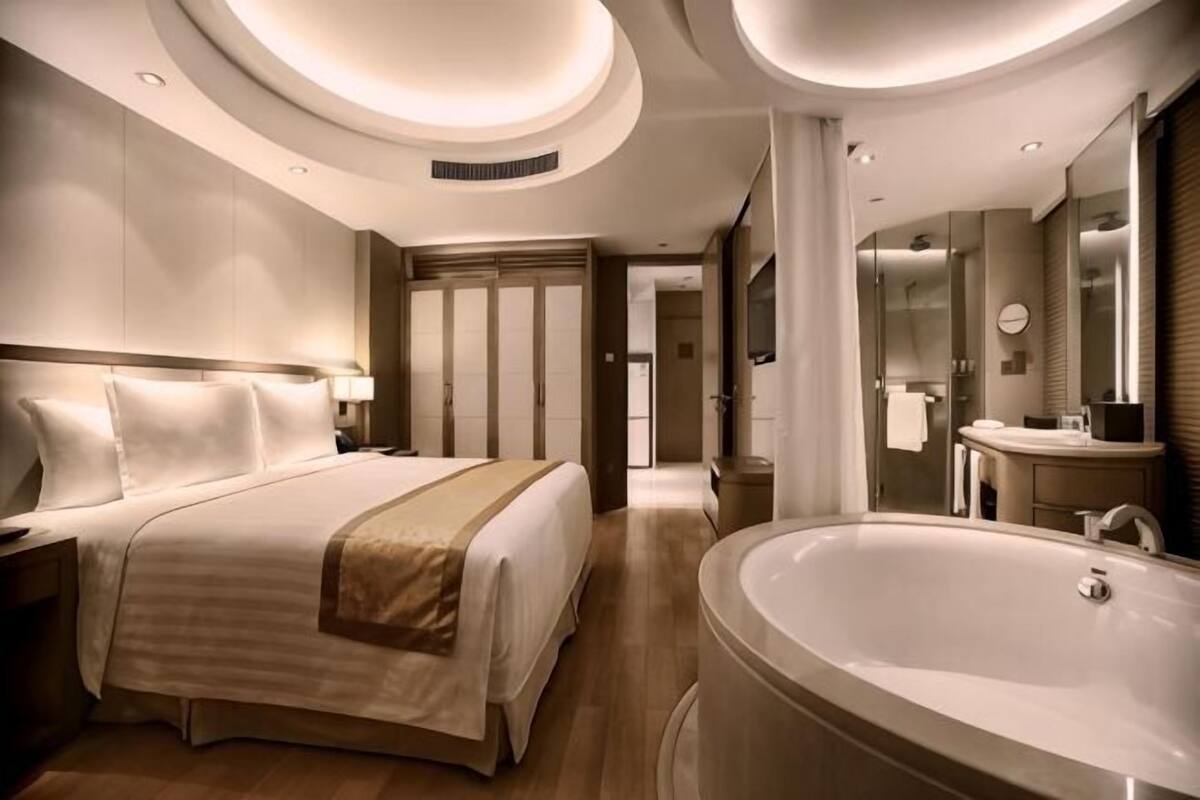 A modern hotel room with a large bed, a separate bathroom with a bathtub, and a walk-in closet.